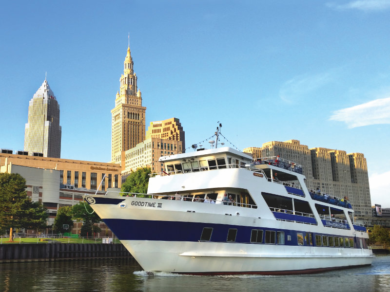 Private Charters goodtimeiii boat, cruising down the river, with the city in the background