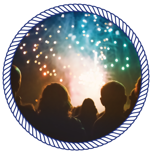 group of people watching fireworks go off over the water